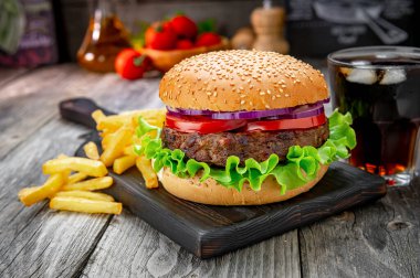 Domatesli ızgara sığır burger, soğan ve kızarmış patates. Restoranda nefis ızgara yemekler.