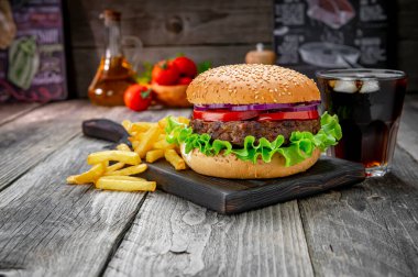 Domatesli ızgara sığır burger, soğan ve kızarmış patates. Restoranda nefis ızgara yemekler.