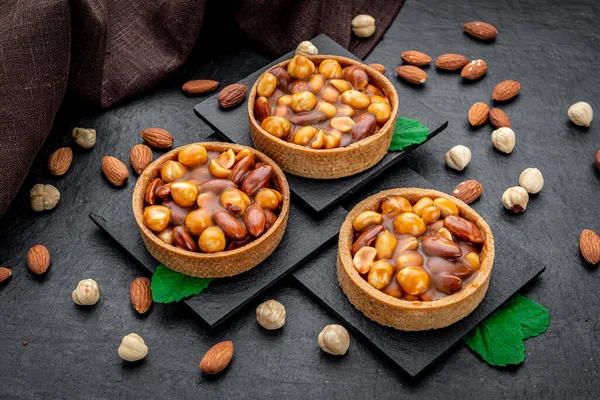 Nut tartlet with hazelnuts, almonds and caramel. Traditional pastry - Butterscotch tartlet with hazelnut, almond and pecan. Autumn dessert