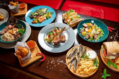 Different colorful meals on dark wooden table in the restaurant. Beautiful food background