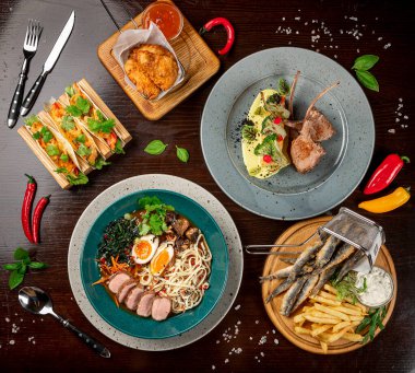 Different colorful meals on dark wooden table in the restaurant. Beautiful food background
