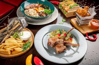 Different colorful meals on dark wooden table in the restaurant. Beautiful food background