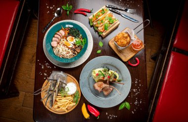 Different colorful meals on dark wooden table in the restaurant. Beautiful food background