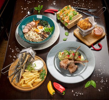 Different colorful meals on dark wooden table in the restaurant. Beautiful food background