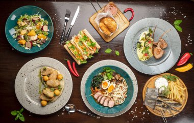 Different colorful meals on dark wooden table in the restaurant. Beautiful food background