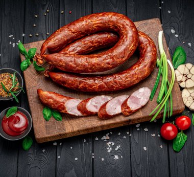 Farklı baharat ve sebzelerle birlikte koyu bir arka planda kurutulmuş domuz sosisi. Menü için fotoğraf