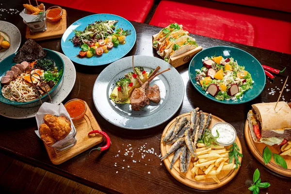 Different colorful meals on dark wooden table in the restaurant. Beautiful food background