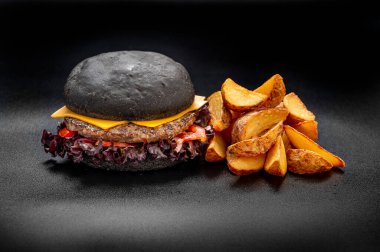 Black beef burger with french fries isolated on black background. Photo for the menu