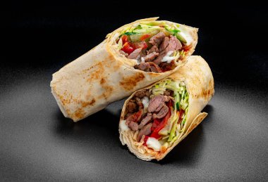 Beef shawarma on a dark background. Shawarma with beef in pita bread. Photo for the menu