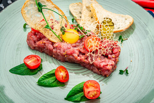 Beef steak tartare with raw egg yolk. French cuisine. Top view. Healthly food. Serving food in a restaurant