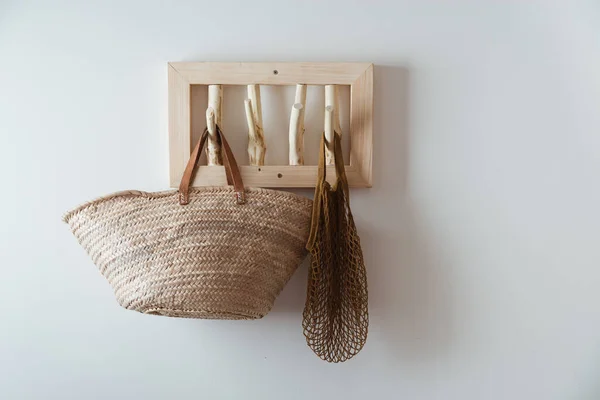 straw bag and mesh bag on handmade wooden hang. Concept of slowlife home. High quality photo