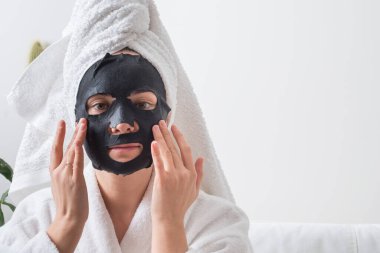 Genç kız, kumaş maskeli güzellik derisi için spa tedavisinden hoşlanıyor. Yüksek kalite fotoğraf