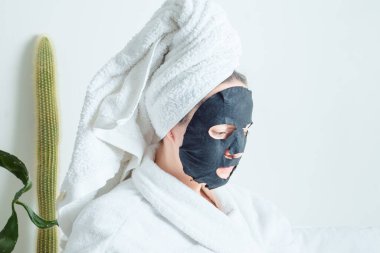 Genç kız, kumaş maskeli güzellik derisi için spa tedavisinden hoşlanıyor. Yüksek kalite fotoğraf