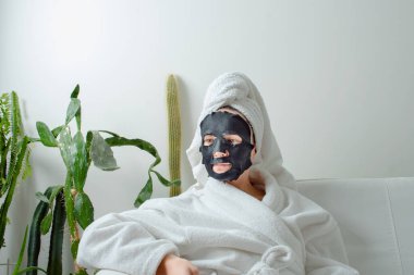 Genç kız, kumaş maskeli güzellik derisi için spa tedavisinden hoşlanıyor. Yüksek kalite fotoğraf