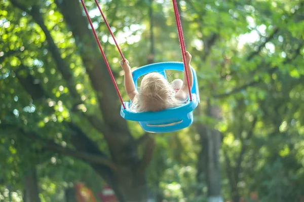 toddler girl on a swing in the park. High quality photo
