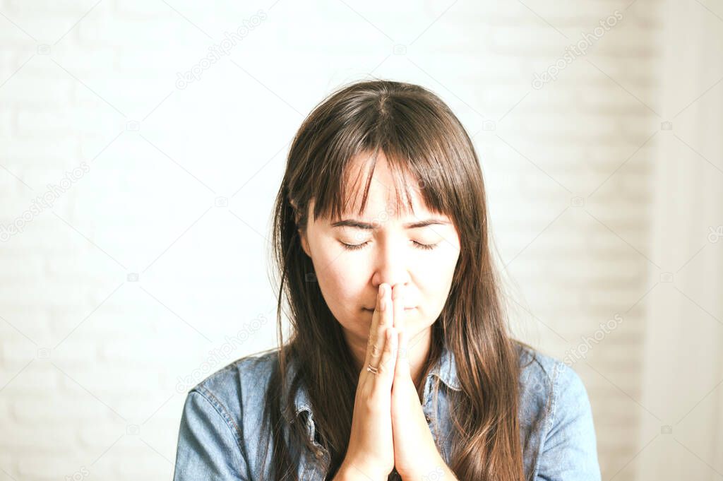 emotional woman praying on a light background. High quality photo 