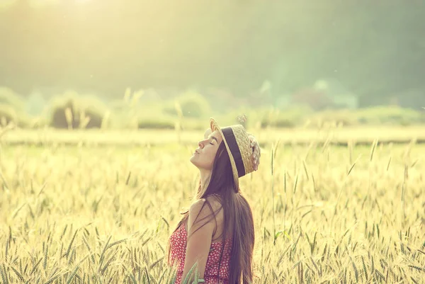 夏を楽しむ麦畑の真ん中にある麦藁帽子の若い女性 — ストック写真