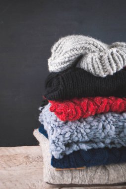 Siyah ahşap arka planda örülmüş renkli ve desenli kumaşlar.