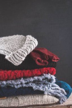 Siyah ahşap arka planda örülmüş renkli ve desenli kumaşlar.