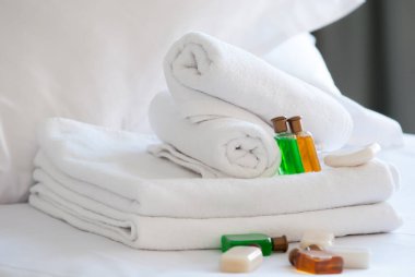 Otelin yatağında beyaz, saf havlular ve sabun jelleri.