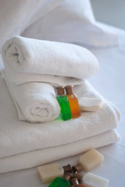 Otelin yatağında beyaz, saf havlular ve sabun jelleri.