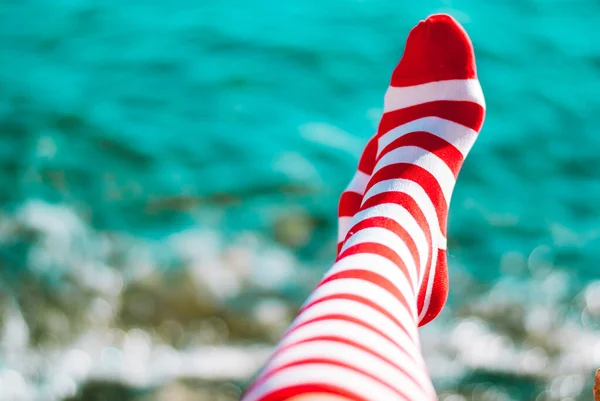 Concept of summer vacation with red striped socks on sea background
