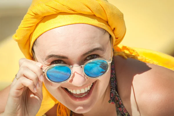 幸せな若い女性を笑顔で青いサングラスと黄色のスカーフ — ストック写真
