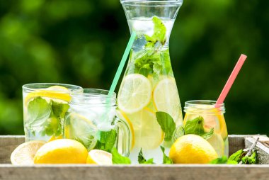 Sürahide ev yapımı limonata ve nane ve limonlu kavanozlar.