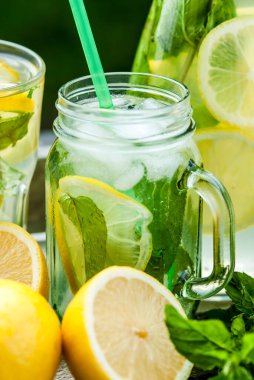 Sürahide ev yapımı limonata ve nane ve limonlu kavanozlar.