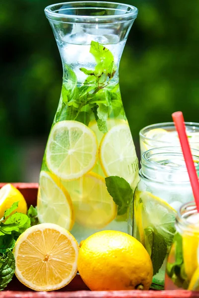 Sürahide ev yapımı limonata ve nane ve limonlu kavanozlar.