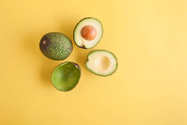 Üst manzara, sarı arka planda izole edilmiş avokadoların stüdyo fotoğrafı. 