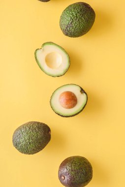 Üst manzara, sarı arka planda izole edilmiş avokadoların stüdyo fotoğrafı. 