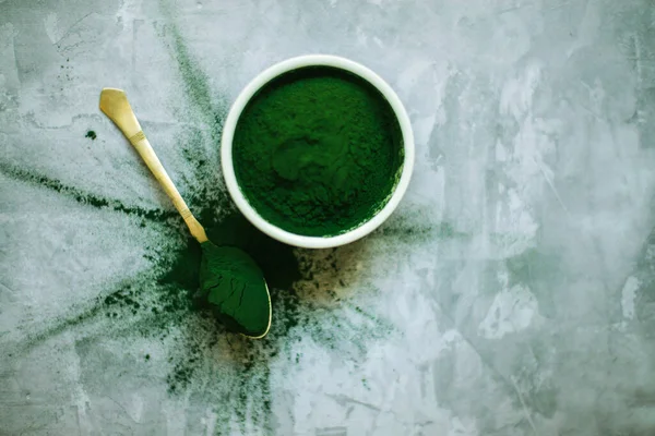 spirulina powder and tablets in white plates on concrete background. top view