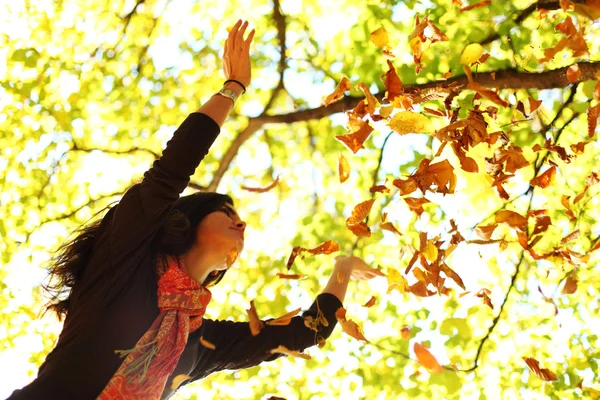 Vrouw drop bladeren in de herfst park — Stockfoto