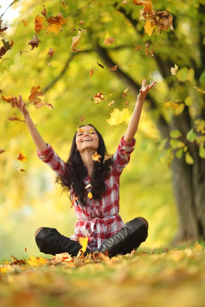 Vrouw drop bladeren in de herfst park Stockfoto