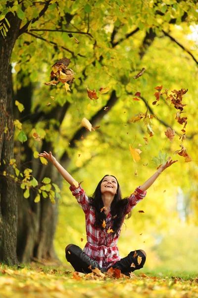 Vrouw drop bladeren in de herfst park Stockafbeelding