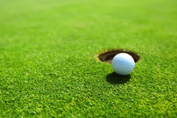 Pallina da golf sul labbro della tazza — Foto Stock