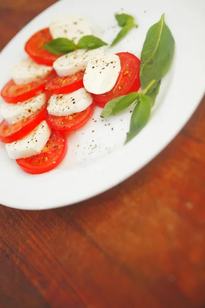Моцарелла с сыром помидор и базилик на тарелке — стоковое фото
