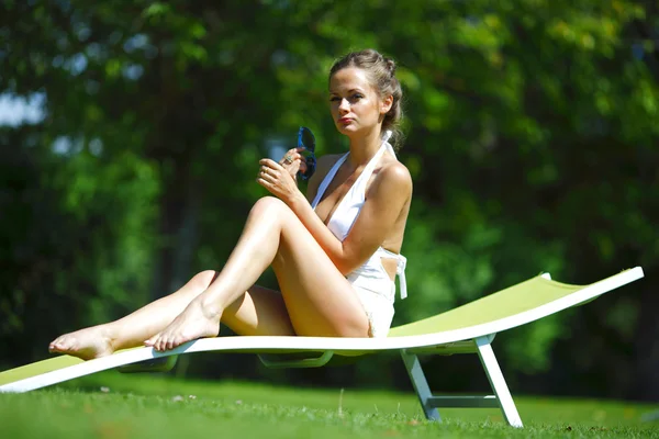 Meisje zit in een witte lounge op een groen gras — Stockfoto
