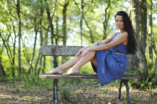 Mujer joven sentada en el banco en el parque — Foto de Stock