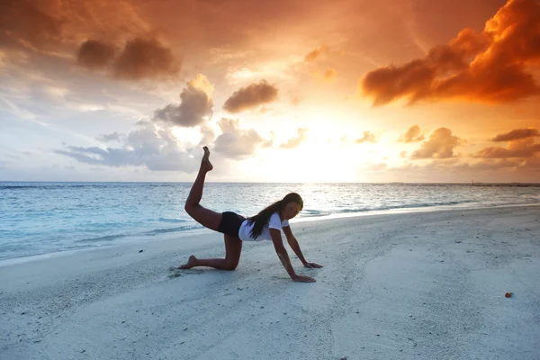 Joga kobieta na plaży o zachodzie słońca — Zdjęcie stockowe