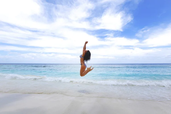 Junge Frau springt an einen Strand — Stockfoto