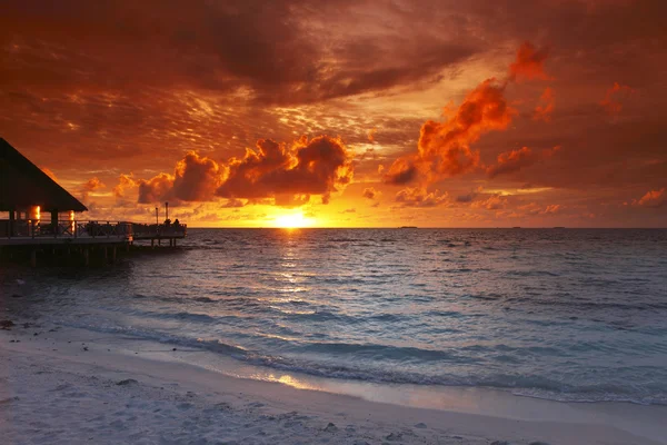 Strand en tropische huizen op zonsondergang — Stockfoto