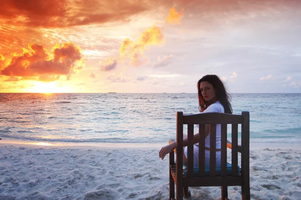 Frau sitzt bei Sonnenuntergang auf Strandkorb — Stockfoto
