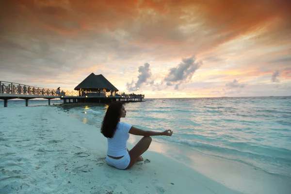 Yoga vrouw op het strand bij zonsondergang — Stockfoto