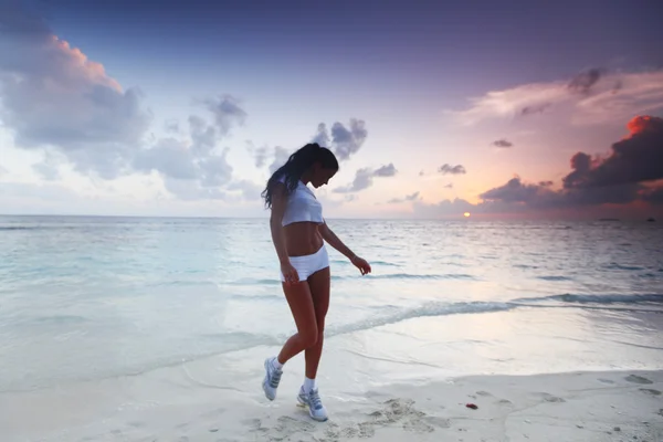 Vrouw in sportkleding op strand — Stockfoto