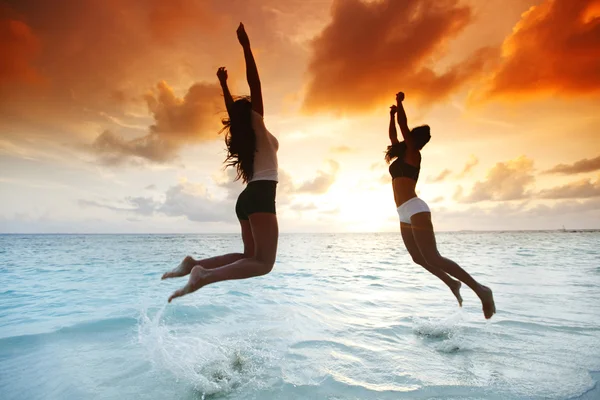 Twee gelukkige vrouwen springen op strand — Stockfoto