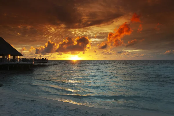 Strand und tropische Häuser bei Sonnenuntergang — Stockfoto