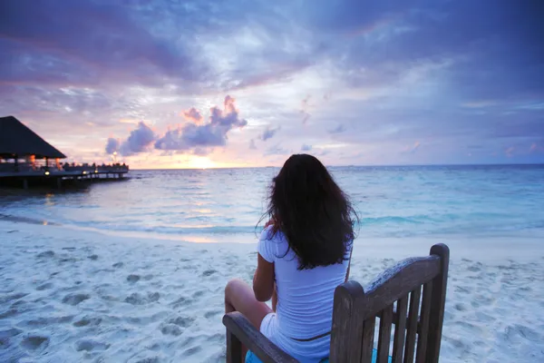 Mulher sentada na cadeira de praia ao pôr do sol — Fotografia de Stock