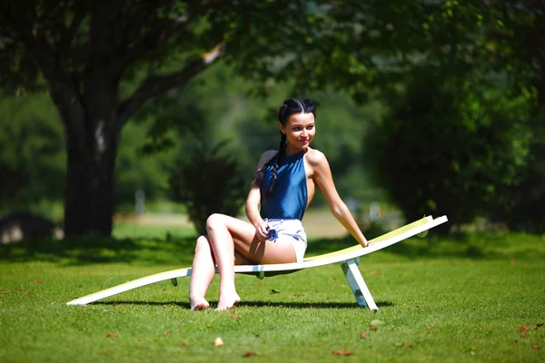 Fille assise dans un salon blanc sur une herbe verte — Photo